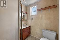 Bathroom featuring a wood vanity with integrated sink, framed mirror, and a window - 