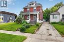 Two-story brick exterior featuring a covered front porch with white columns, a dormer window, and a concrete driveway - 26 Arthur Avenue, St. Thomas, ON 
