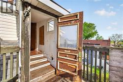 Exterior wooden door with glass pane, wooden railing, and partial siding - 