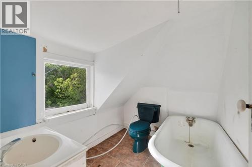 Bathroom featuring a porcelain vanity with a built-in sink, a window overlooking trees, a colored toilet, a classic clawfoot bathtub, and tiled flooring - 26 Arthur Avenue, St. Thomas, ON - Indoor Photo Showing Bathroom