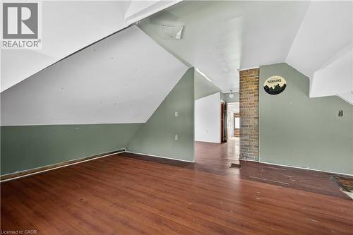 Open room featuring wood-finish flooring, a partial brick column, and sloped ceilings - 26 Arthur Avenue, St. Thomas, ON - Indoor Photo Showing Other Room