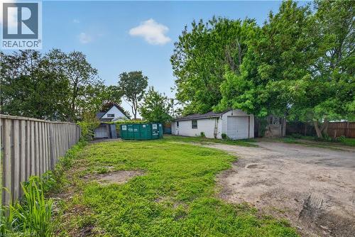 Spacious property offering a gravel driveway, a detached garage, and a separate shed, all surrounded by mature trees - 26 Arthur Avenue, St. Thomas, ON - Outdoor