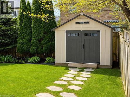 Cream-colored shed with dark gray double doors, transom windows, and a dark shingle roof - 51 Redtail Crescent, Hamilton, ON 