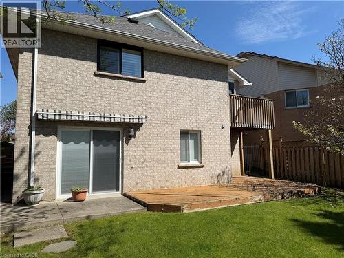 Rear exterior featuring light-colored brick, a second-story balcony, and a ground-level deck - 51 Redtail Crescent, Hamilton, ON 