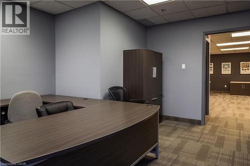 Office space featuring a U-shaped desk with a wood-finish surface, recessed lighting, and patterned carpet flooring - 5100 South Service Road, Burlington, ON 