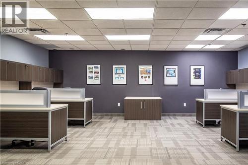 Spacious office interior with modular workstations, built-in overhead cabinetry, and patterned carpet flooring - 5100 South Service Road, Burlington, ON 