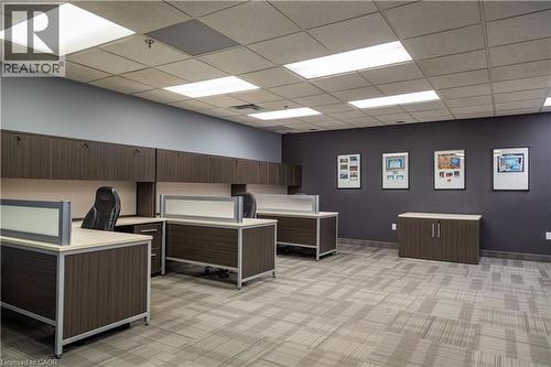 Open-plan office area featuring modular workstations with privacy panels, wood-finish cabinetry, and suspended acoustic ceiling tiles with integrated lighting - 5100 South Service Road, Burlington, ON 