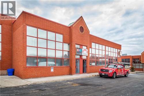Brick commercial building featuring large grid-pane windows, a prominent gable facade, and a paved parking area - 5100 South Service Road, Burlington, ON 