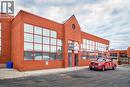 Brick commercial building featuring large grid-pane windows, a prominent gable facade, and a paved parking area - 5100 South Service Road, Burlington, ON 