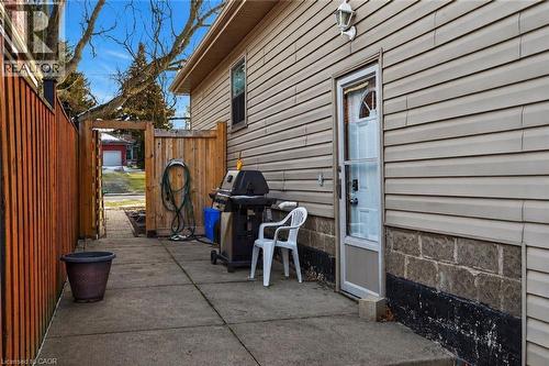 Concrete patio with a wood privacy fence, leading to a wooden gate and a rear entry door - 258 Sanatorium Road, Hamilton, ON 