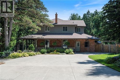 Traditional two-story residence featuring a brick and siding exterior, a full-width covered porch with wood columns, and a prominent brick chimney - 182 Governors Road E, Paris, ON 