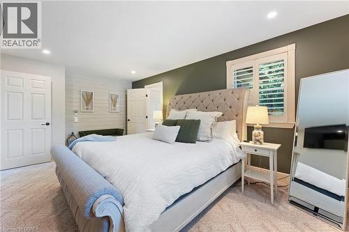 Recessed ceiling lighting illuminates a room featuring a textured accent wall and a window with plantation shutters - 182 Governors Road E, Paris, ON 
