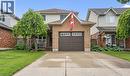 Brick and siding exterior with an attached garage, featuring a concrete driveway and a covered front porch - 817 Acadia Drive, Hamilton, ON  - Outdoor With Facade 