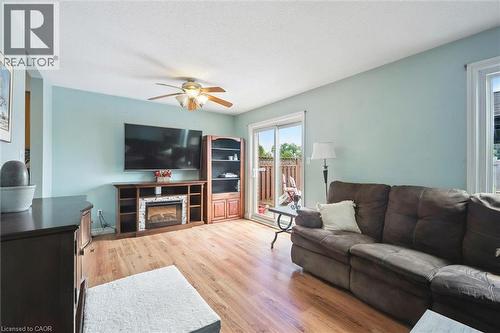 Living area featuring wood-finish flooring, a built-in electric fireplace media console, and a ceiling fan - 817 Acadia Drive, Hamilton, ON - Indoor Photo Showing Living Room