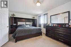 Carpeted bedroom featuring a built-in dark wood headboard unit with integrated shelving and cabinetry - 