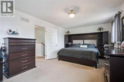 Carpeted room featuring a ceiling-mounted light fixture, white interior door, and a built-in headboard storage unit - 