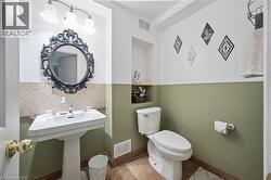 Pedestal sink with chrome fixtures, an ornate dark-framed mirror, and a three-light vanity fixture - 