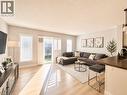 Open-concept living area featuring light wood-finish flooring, white walls, and a sliding glass door with plantation shutters. Staged with AI - 1333 Countrystone Drive, Kitchener, ON 