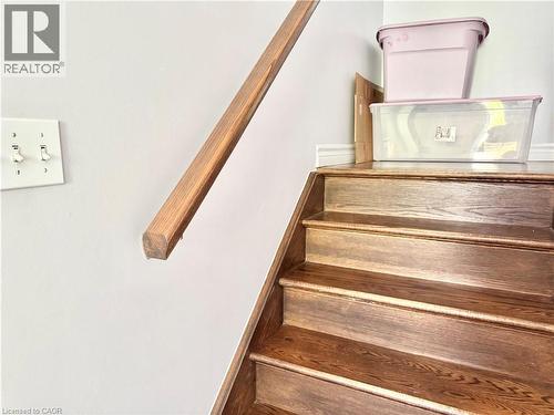 Wood-finish staircase with coordinating wood handrail and light-colored wall - 1333 Countrystone Drive, Kitchener, ON 