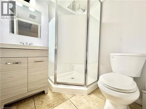 Corner shower with clear glass enclosure and frosted panels, complemented by a wood-finish vanity with a rectangular sink and chrome faucet - 1333 Countrystone Drive, Kitchener, ON 