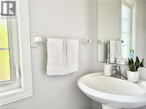Pedestal sink with chrome faucet, complemented by a large wall-mounted mirror - 1333 Countrystone Drive, Kitchener, ON 