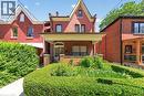 Red brick facade with a covered front porch featuring decorative metal columns - 16 Mulberry Street, Hamilton, ON 