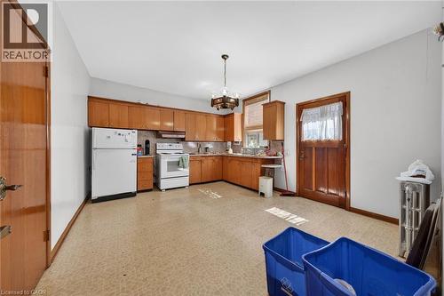 Expansive kitchen featuring wood cabinetry, a built-in oven, refrigerator, and a matching wood door - 16 Mulberry Street, Hamilton, ON 