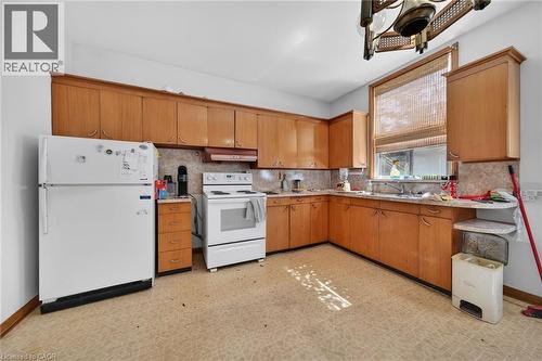 Kitchen featuring extensive wood-finish cabinetry, a large window with natural light, patterned flooring, and a built-in kitchen sink - 16 Mulberry Street, Hamilton, ON 