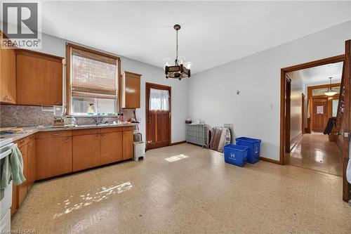 Kitchen featuring wood-finish cabinetry, a window with natural light, and a patterned flooring - 16 Mulberry Street, Hamilton, ON 