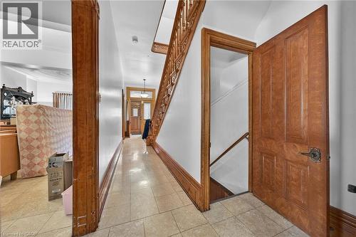 Entryway featuring wood-finish flooring, a detailed wooden staircase, and solid wooden doors with ornate hardware - 16 Mulberry Street, Hamilton, ON 