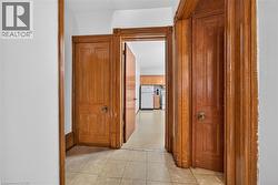 Hallway featuring light-toned square tile flooring and white walls - 