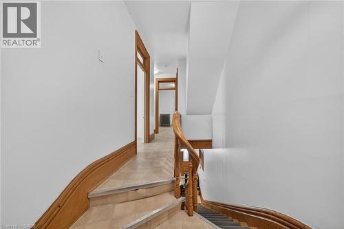 Staircase with wood newel and handrail, gray stair runner, and light-toned risers - 16 Mulberry Street, Hamilton, ON 