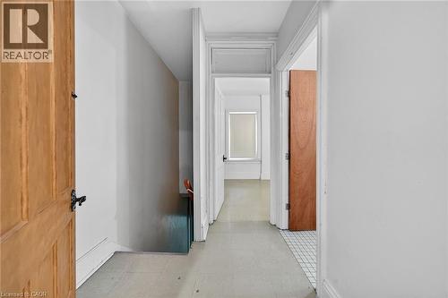 Hallway with light-toned flooring, white walls, and wood panel doors - 16 Mulberry Street, Hamilton, ON 