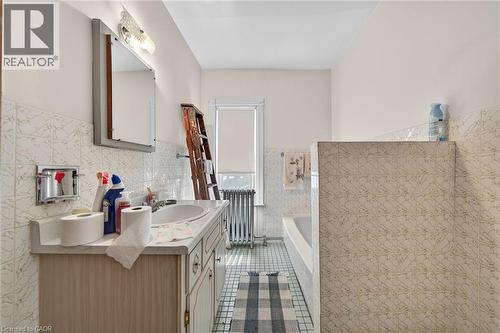 Bathroom vanity with integrated sink, patterned wall tile, and light-colored floor tiles - 16 Mulberry Street, Hamilton, ON 
