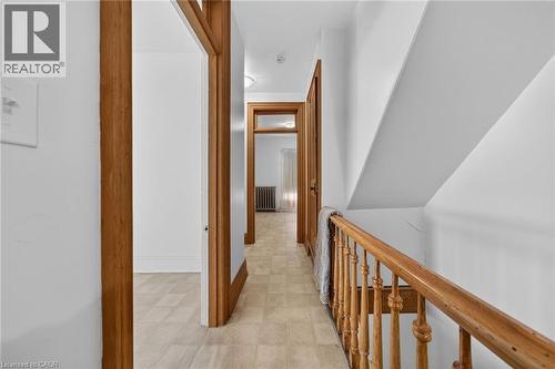 Hallway featuring wood-finish trim and doors, neutral wall paint, and geometric-patterned flooring - 16 Mulberry Street, Hamilton, ON 