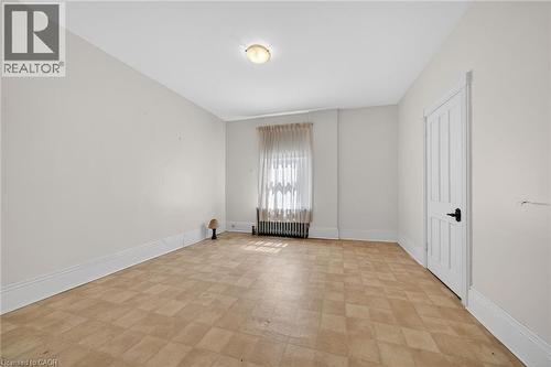 Room featuring light-toned walls, patterned flooring, and a single window with curtain rods - 16 Mulberry Street, Hamilton, ON 