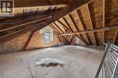 Expansive attic space featuring exposed brick walls, visible wood beam construction, and multiple window openings - 16 Mulberry Street, Hamilton, ON 
