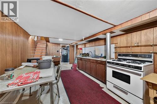 Basement space featuring wood-finish paneling, an exposed beam ceiling, a full-size range, and a sink with lower cabinetry - 16 Mulberry Street, Hamilton, ON 