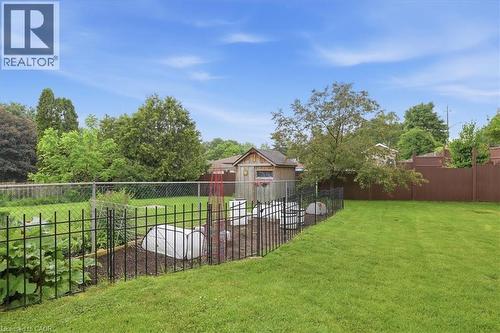 Expansive green lawn with a dedicated garden area, featuring a decorative black metal fence - 116 Scott Road, Cambridge, ON 