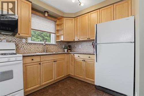 Kitchen featuring light wood cabinetry, mosaic tile backsplash, solid surface countertops, and a window above the sink - 116 Scott Road, Cambridge, ON 