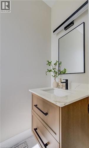 Modern vanity featuring a light wood-finish cabinet with black hardware, a white countertop, an undermount sink, and a black-framed rectangular mirror - 210 Heritage Drive Unit# Upper, Kitchener, ON 