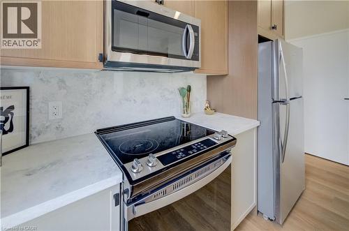Kitchen featuring stainless steel appliances, light wood-finish cabinetry, a smooth-top electric range, a built-in microwave, and light-toned countertops with a matching backsplash - 210 Heritage Drive Unit# Upper, Kitchener, ON 