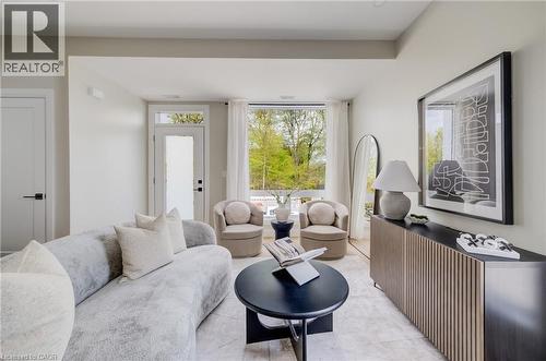 Living space featuring abundant natural light, a full-lite glass door, and large windows showcasing tree-lined surroundings - 210 Heritage Drive Unit# Upper, Kitchener, ON 