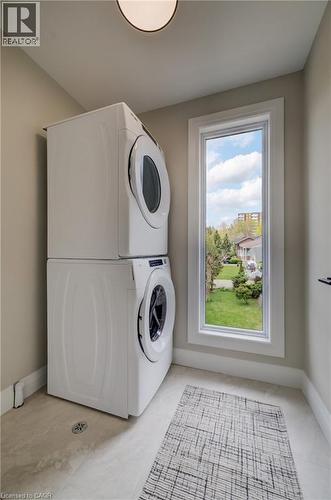 Laundry area with stacked appliances, a single window, light-toned wall paint, and tile flooring - 210 Heritage Drive Unit# Upper, Kitchener, ON 
