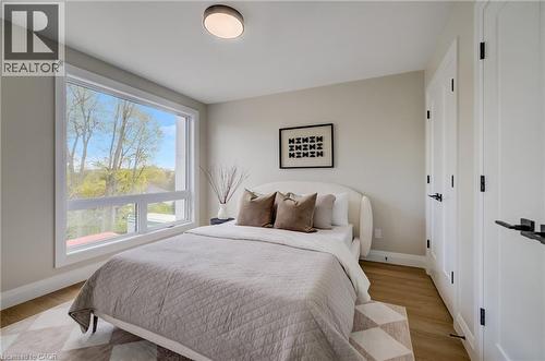 Bedroom featuring wood-finish flooring, a contemporary window, and two paneled doors with matte black hardware - 210 Heritage Drive Unit# Upper, Kitchener, ON 