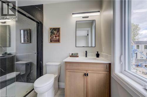 Modern bathroom featuring a glass-enclosed shower with black-frame detailing, a single vanity with wood-finish cabinetry, a white countertop, and a contemporary black faucet - 210 Heritage Drive Unit# Upper, Kitchener, ON 
