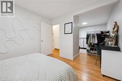 Bedroom featuring wood-finish flooring and an open doorway to a walk-in closet with a visible skylight - 