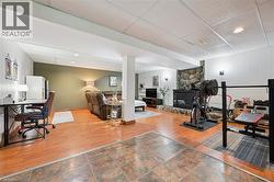 Lower level featuring distinct activity zones, a stone fireplace, wood-finish flooring, recessed lighting, and wall sconces - 