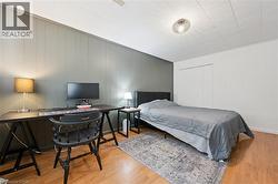 Interior room featuring wood-finish flooring, two-tone wall paneling, and a white grid ceiling - 