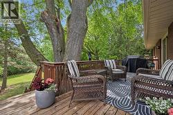 Spacious wood deck featuring a wooden railing, string lights, and mature tree canopy - 